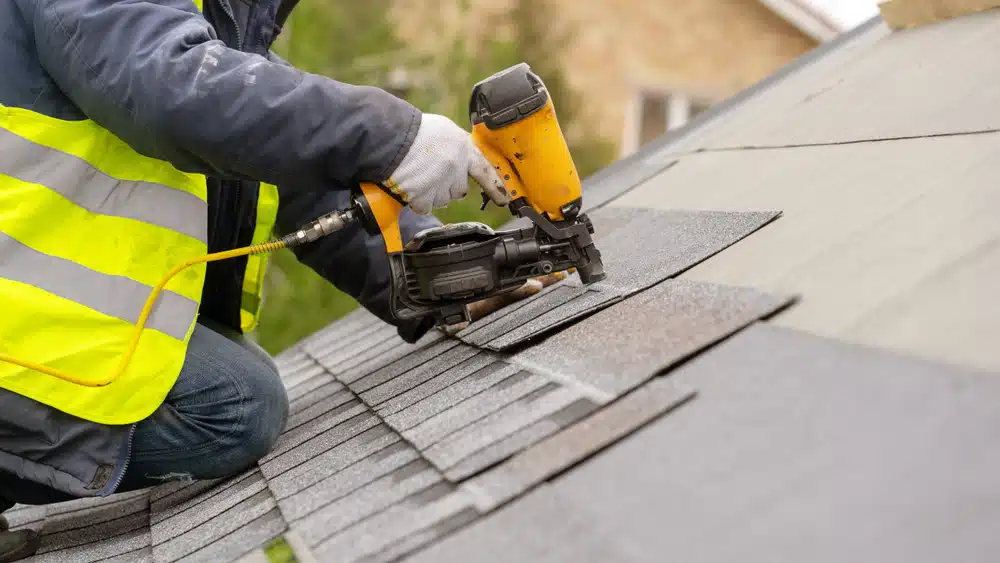 Roofer at work on an asphalt shingle roof